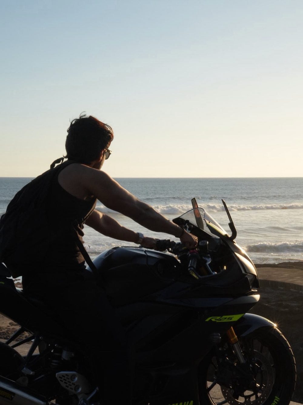 Man riding a motorcycle beside the ocean at sunset